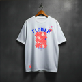 White t-shirt with colorful floral design and text on a hanger against a dark background