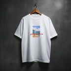 White t-shirt with a graphic design of a sailboat and text 'greetings from the sea' on the front chest