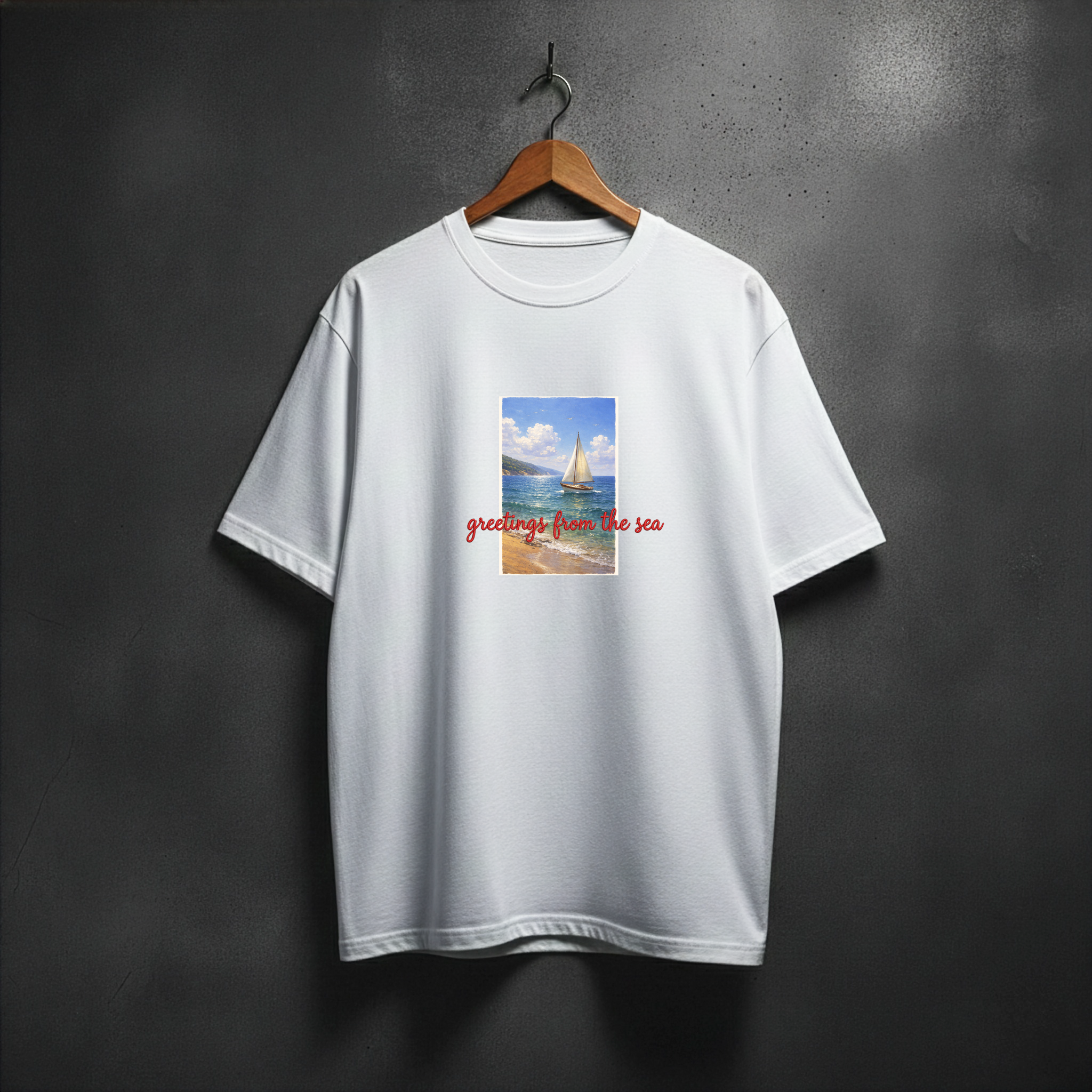 White t-shirt with a graphic design of a sailboat and text 'greetings from the sea' on the front chest